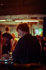 A DJ teaching a small group how to mix tracks in a cozy studio.