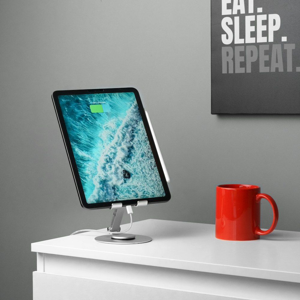 a computer monitor sitting on top of a desk next to a red cup