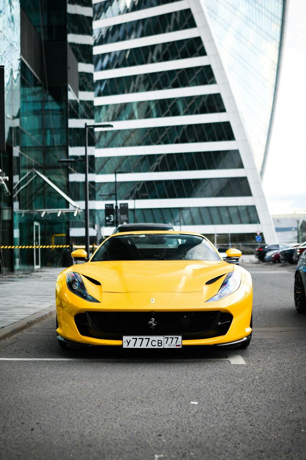 a yellow sports car parked in front of a tall building