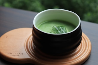 a cup of matcha tea on a wooden plate
