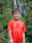 A happy young man wearing a local football team jersey, smiling outdoors.
