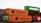 Several shipping containers are stacked in a yard, featuring brands like Hapag-Lloyd and Evergreen. The containers are in various colors including orange and green.