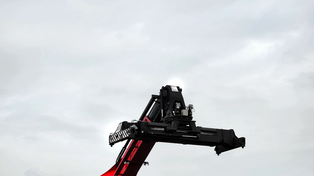 a red crane is lifting a black object into the air