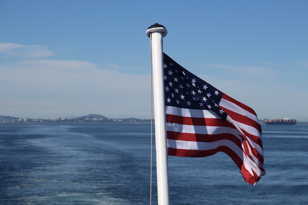 a large american flag flying over a body of water