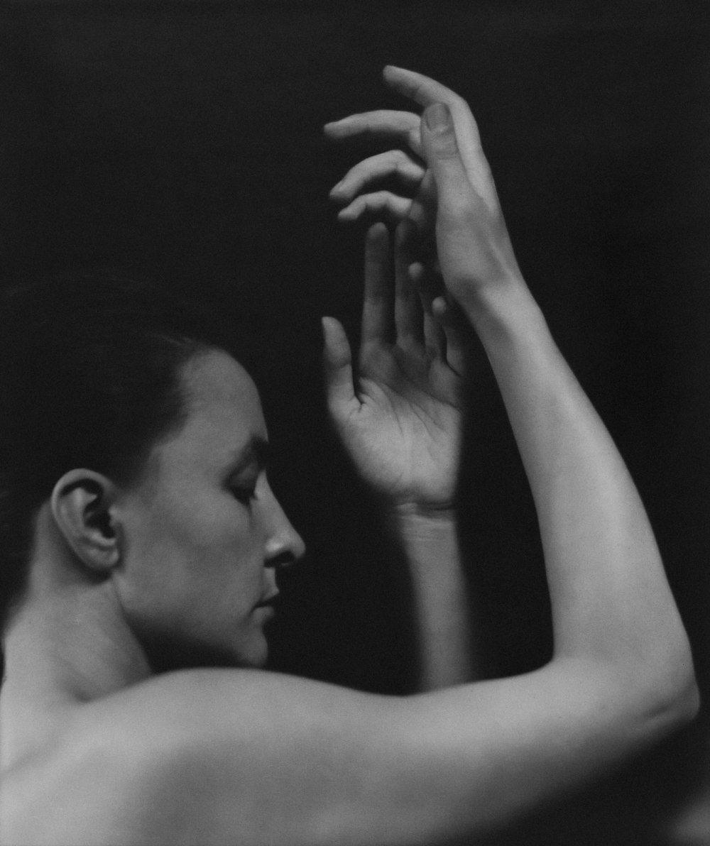 a black and white photo of a woman holding her hands up