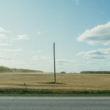 Sunlit vacant lot in Florida with clear skies and utility access markers visible.