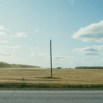 Open land parcel with clear skies and nearby road access.