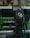 A digital camera is mounted on a tripod, capturing an image of machinery or equipment from a screen. The screen displays a detailed view of the equipment. The setting appears to be industrial with metallic and green components.
