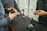 Three individuals are engaged in handling and assembling mechanical arms on a black surface. These extendable arms have base mounts in a cubic shape and appear to be part of a technical or engineering project. The individuals are focused and using their hands actively, implying collaboration or instruction.