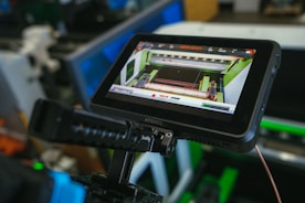 A monitor displaying a digital interface with technical data and graphics, mounted on a piece of equipment. The screen shows various colors and lines, indicating some form of technical or industrial application.