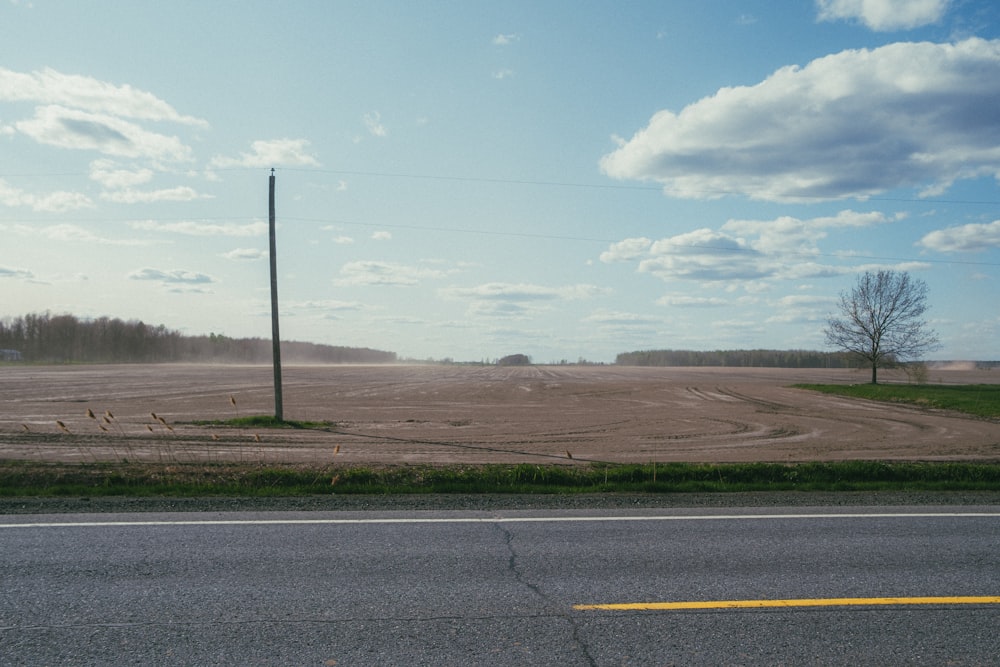 an empty road with a field in the background