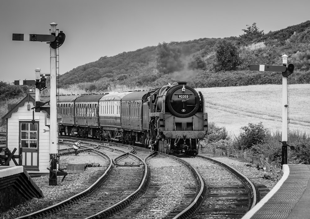 a black and white photo of a train coming down the tracks