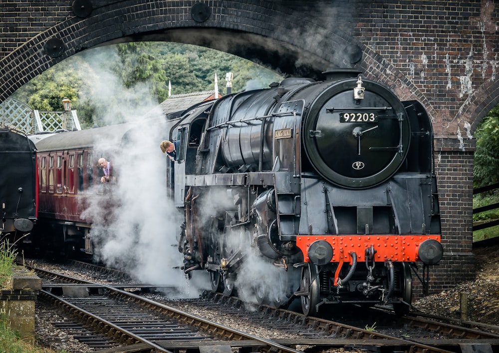 a steam engine train traveling under a bridge