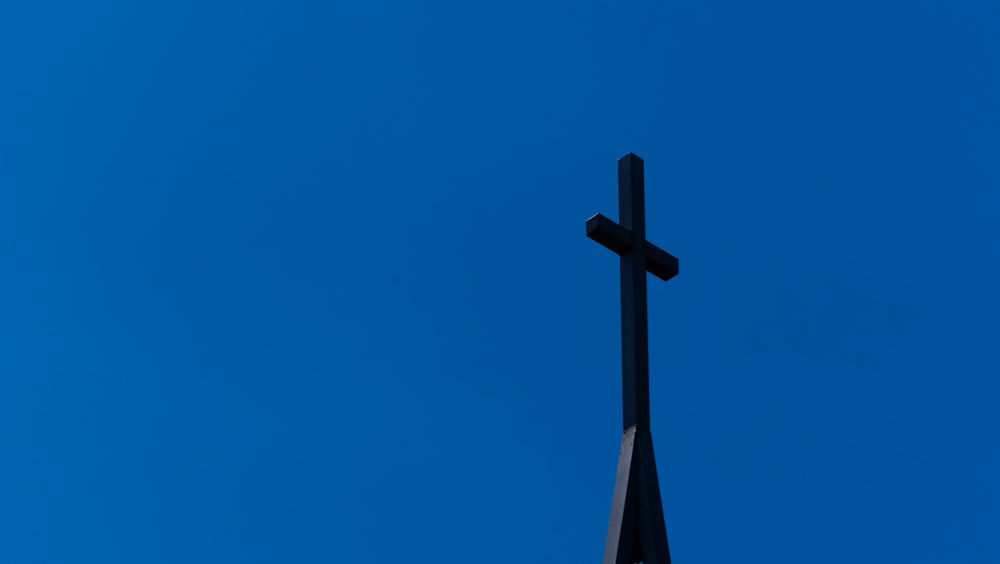 a cross on top of a steeple against a blue sky