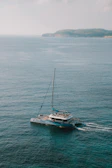 Bob piloting a helicopter over turquoise waters with the catamaran visible below.