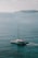 A catamaran with 'Sea Bird' written on its side sails through calm, turquoise waters with an island visible in the distant background under a lightly clouded sky.