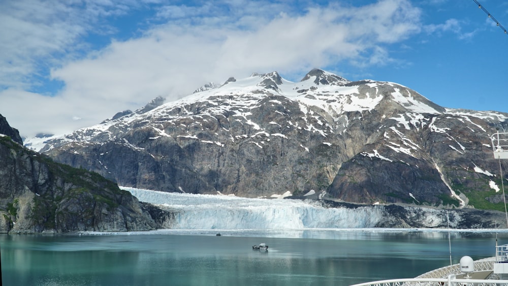 a large mountain covered in snow next to a body of water