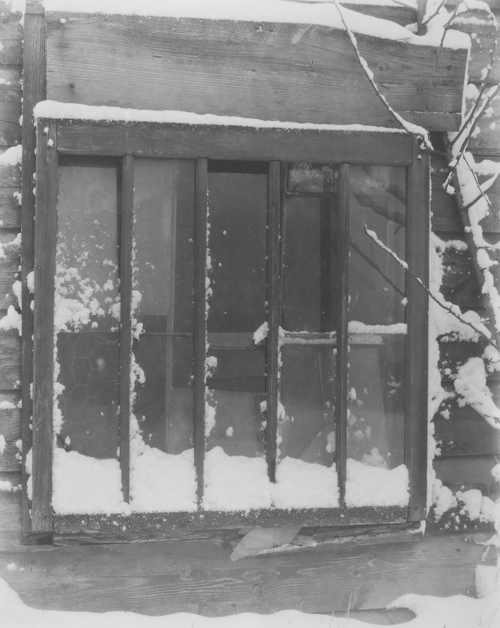 a black and white photo of a window in the snow