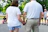 Photo of a happy couple holding hands, with a sunny park setting behind them.