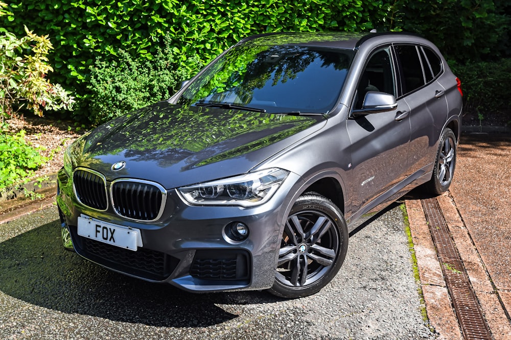 a grey bmw suv parked on the side of a road