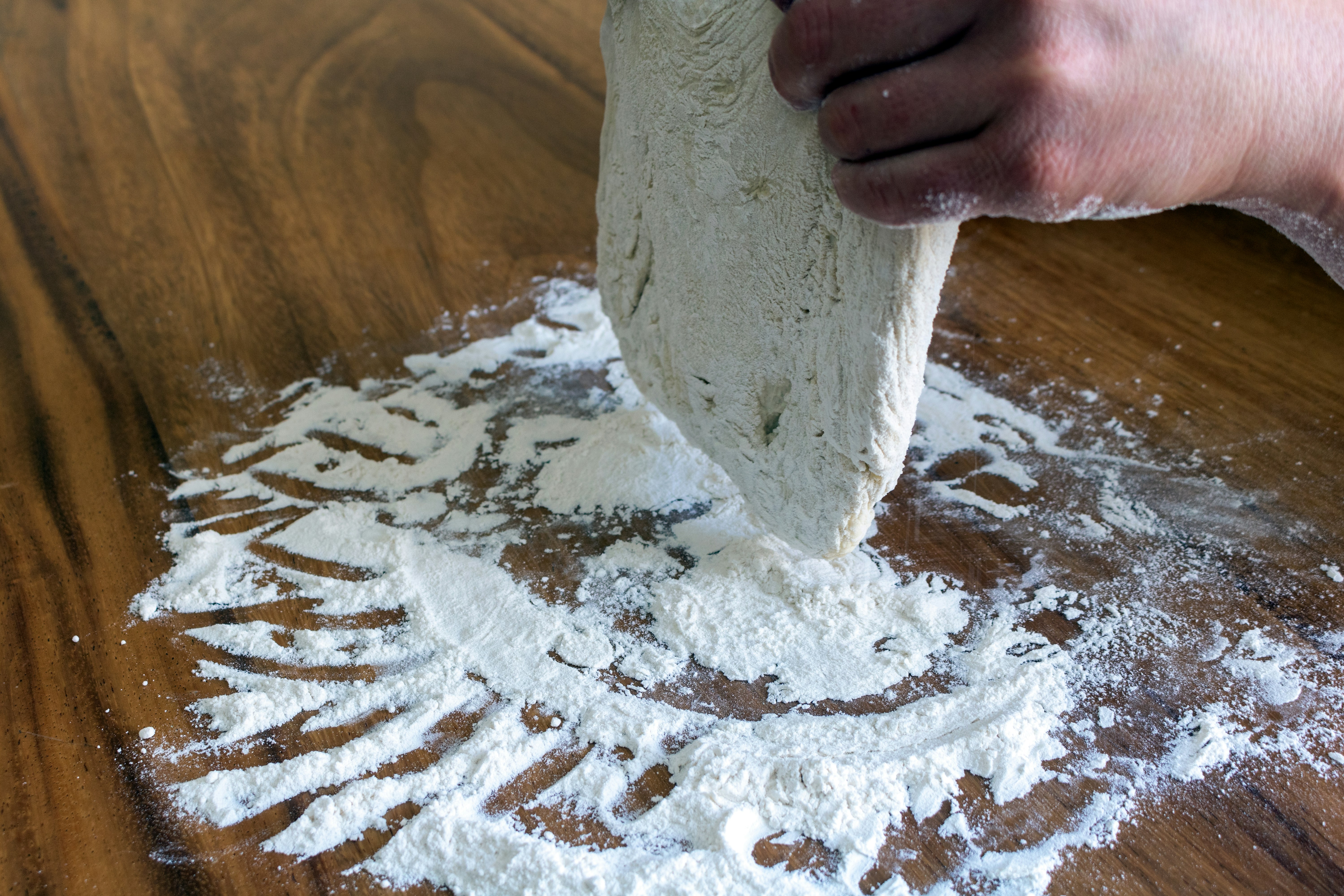 Close-up of fine white flour dusted on a dark wooden surface