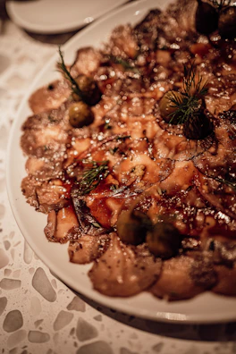 Delicate slices of carpaccio arranged beautifully with a drizzle of olive oil.