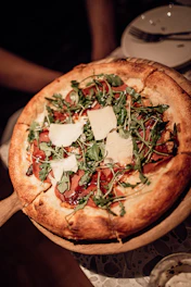 A gourmet pizza slice with arugula, prosciutto, and shaved parmesan on a thin crust.