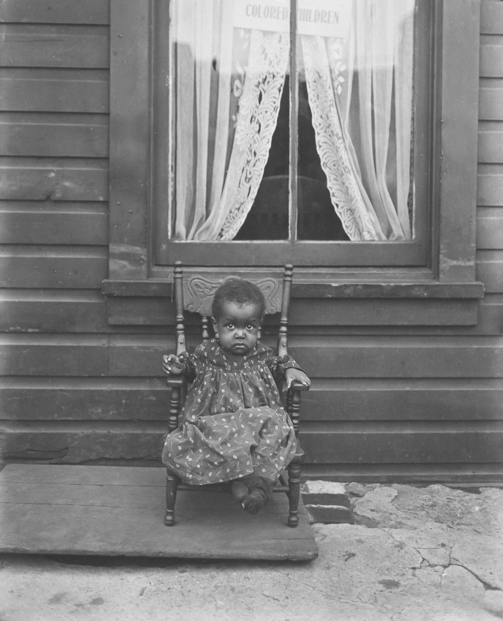 a little girl sitting in a chair in front of a window