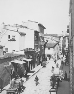 A vintage black and white photograph of a bustling street scene in the 1900s.