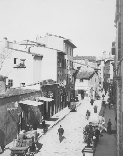 A vintage black and white photograph of a bustling street scene in the 1900s.