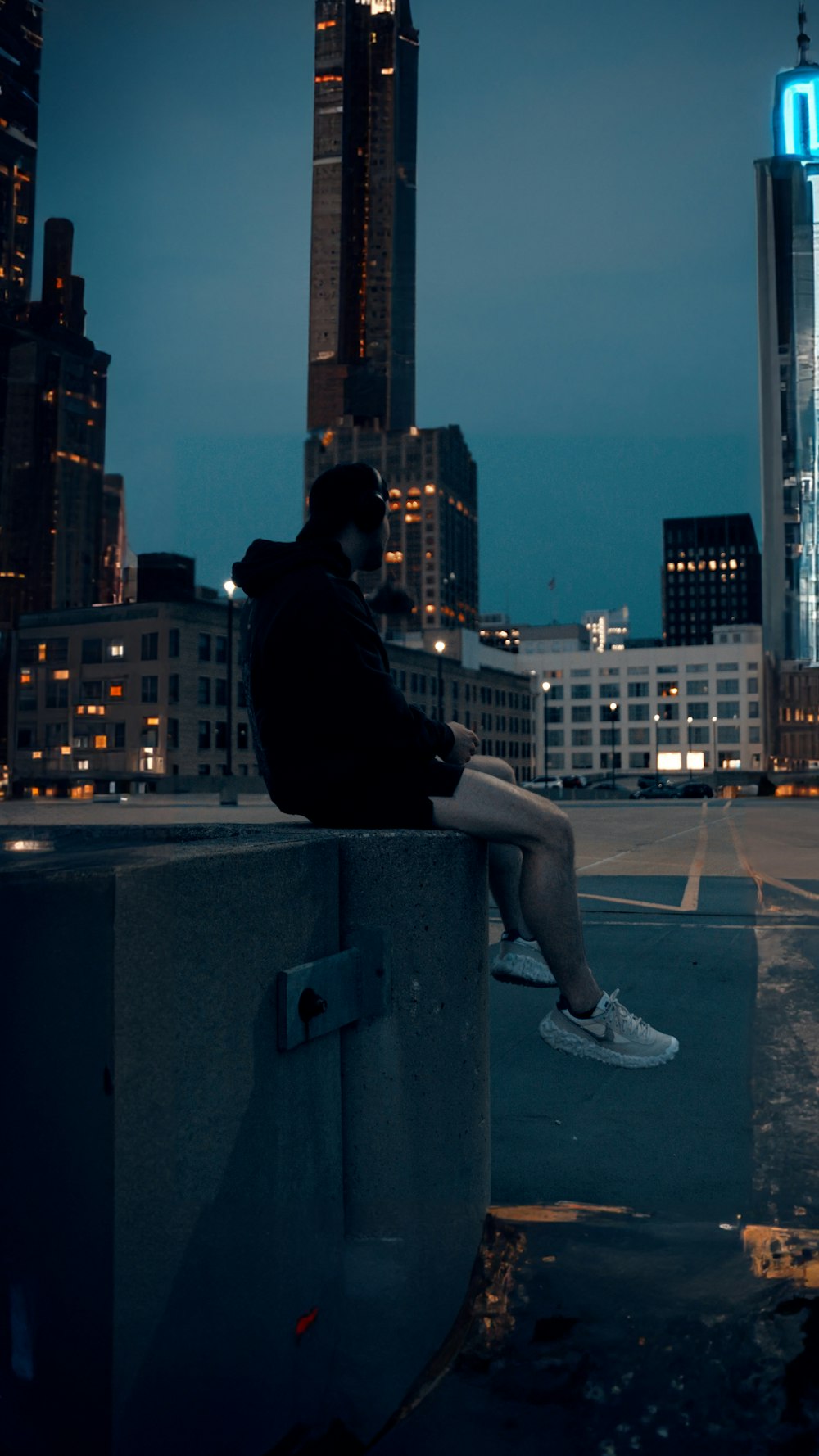 a person sitting on a ledge in front of a city skyline