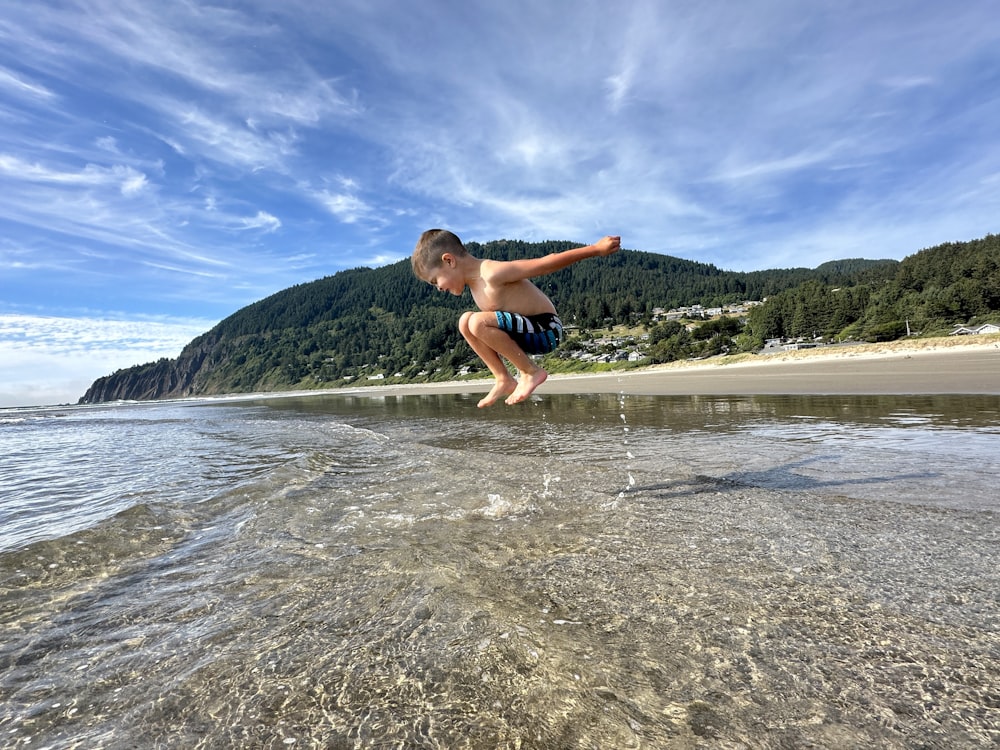 a young boy is playing in the water at the beach