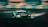A sleek, high-performance racing car is speeding around a track. The car is predominantly black with green and neon accents, featuring various logos and sponsorship decals. Motion blur emphasizes its speed, while the background track and barriers add to the dynamic scene.