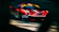 Dynamic shot of a red sports car speeding on a racetrack during sunset.
