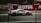 A sleek race car is speeding down a racetrack, with a blurred background that suggests motion. The car is predominantly white with red and black accents and features the number 54 prominently on its side. Advertising and branding are visible, with large logos and designs.