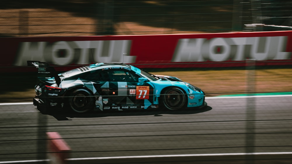 a blue race car driving down a race track