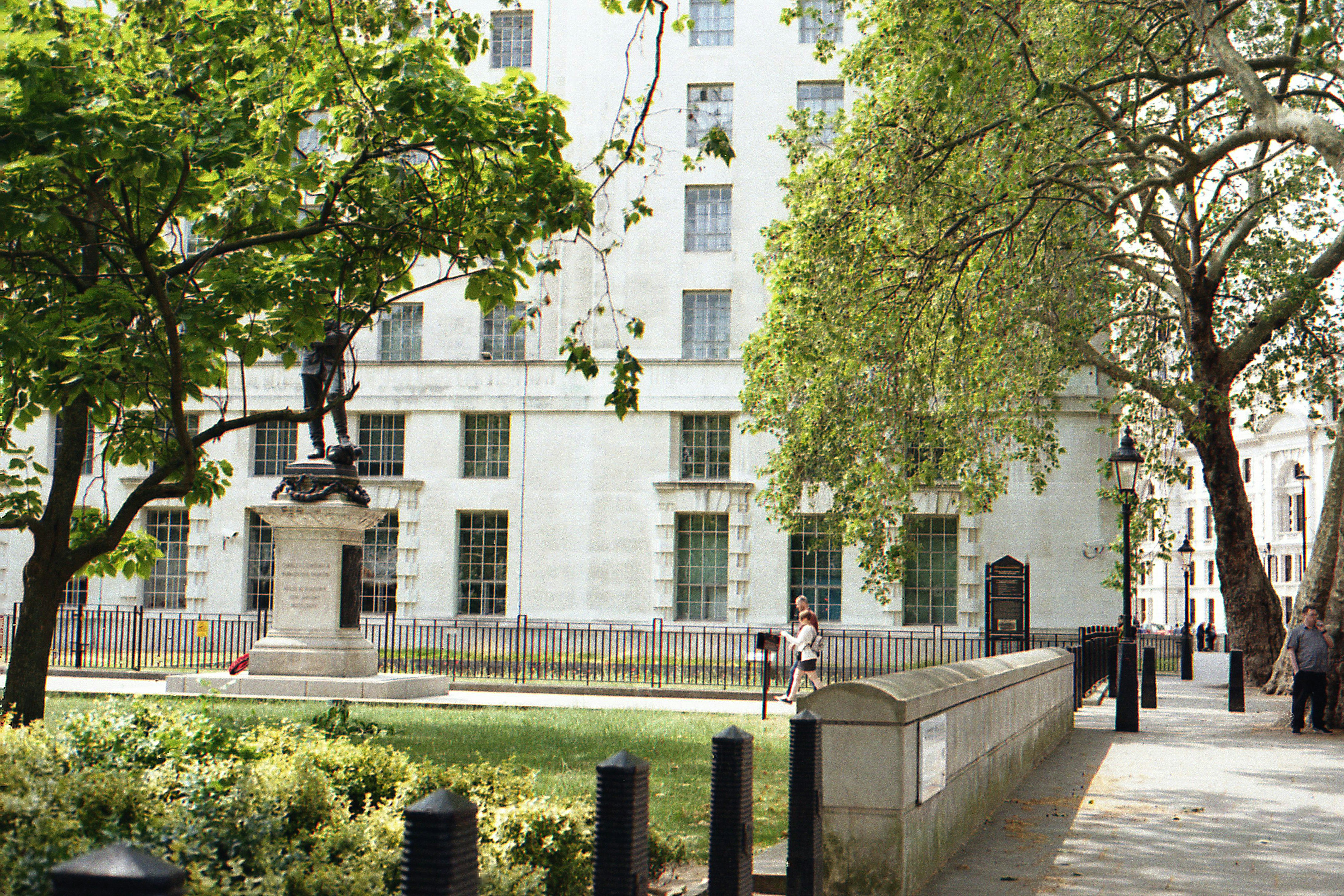 a man walking down a sidewalk next to a tall building