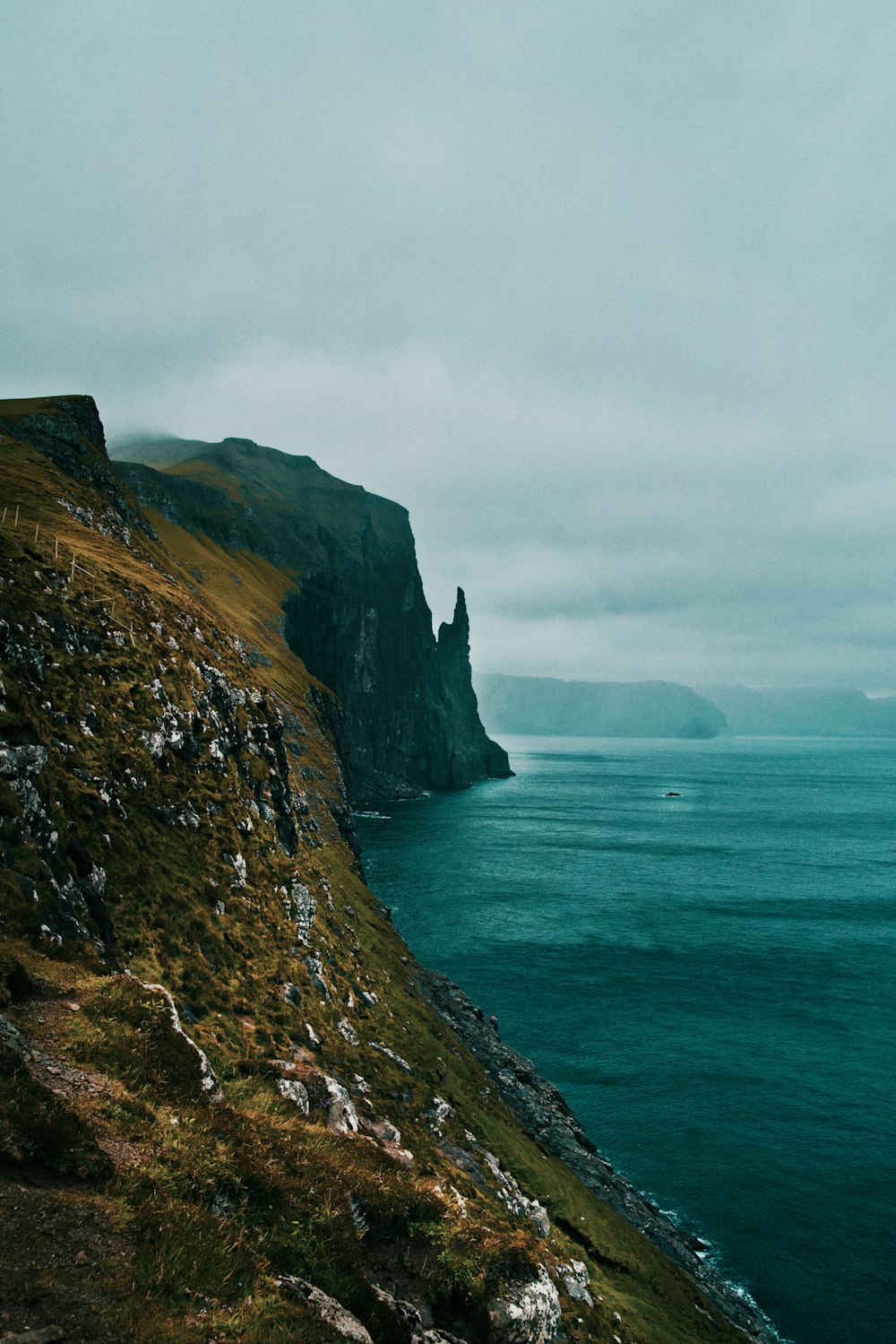 a large body of water sitting next to a lush green hillside