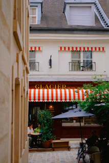 A charming street café in Deauville with striped awnings and people enjoying a sunny afternoon.