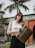 Smiling woman holding a colorful shopping bag with tropical patterns.