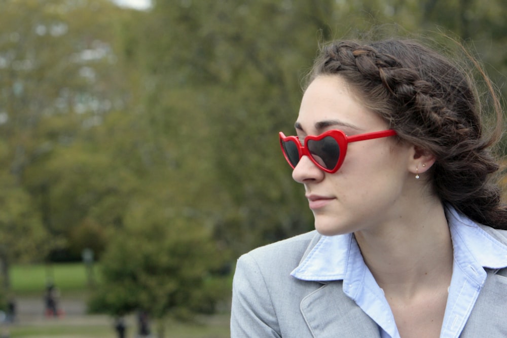 a woman wearing red heart shaped sunglasses in a park