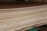 A close-up view of a stack of smooth, evenly cut plywood sheets. The wood grain and layers are visible, indicating high-quality, processed lumber. The sheets are neatly aligned and resting on a green support structure.