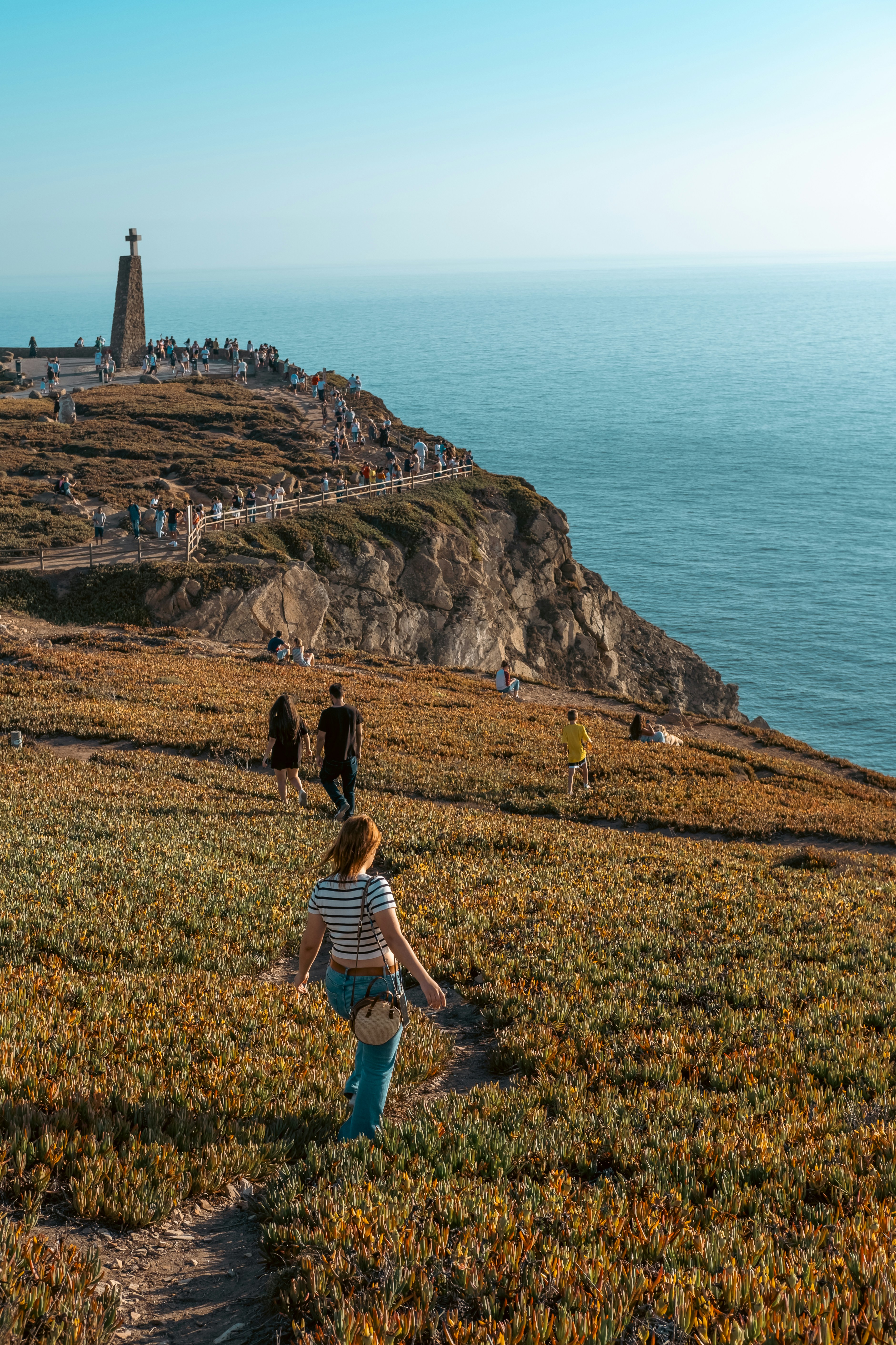 a little boy walking up a hill towards a lighthouse