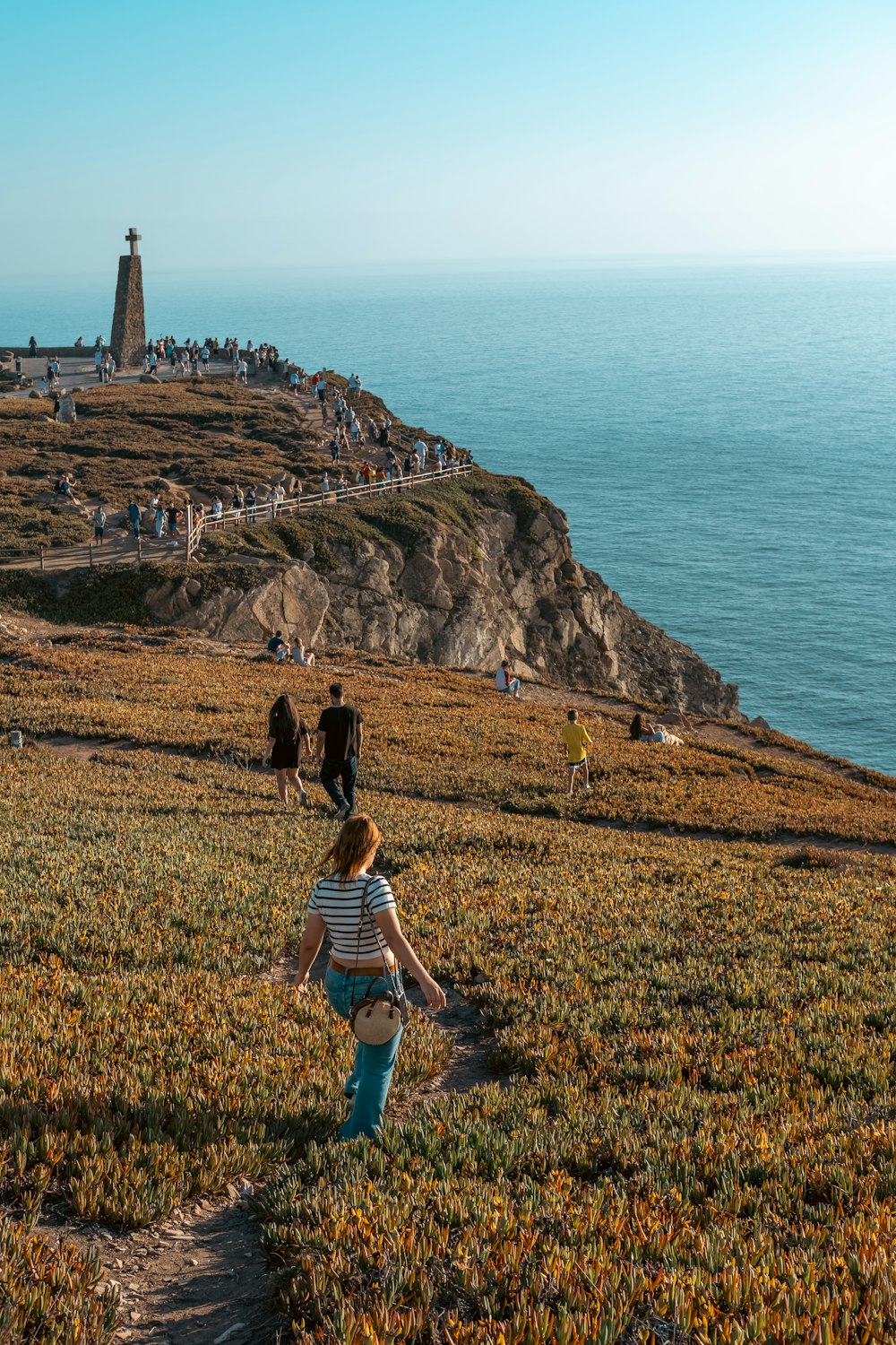 a little boy walking up a hill towards a lighthouse