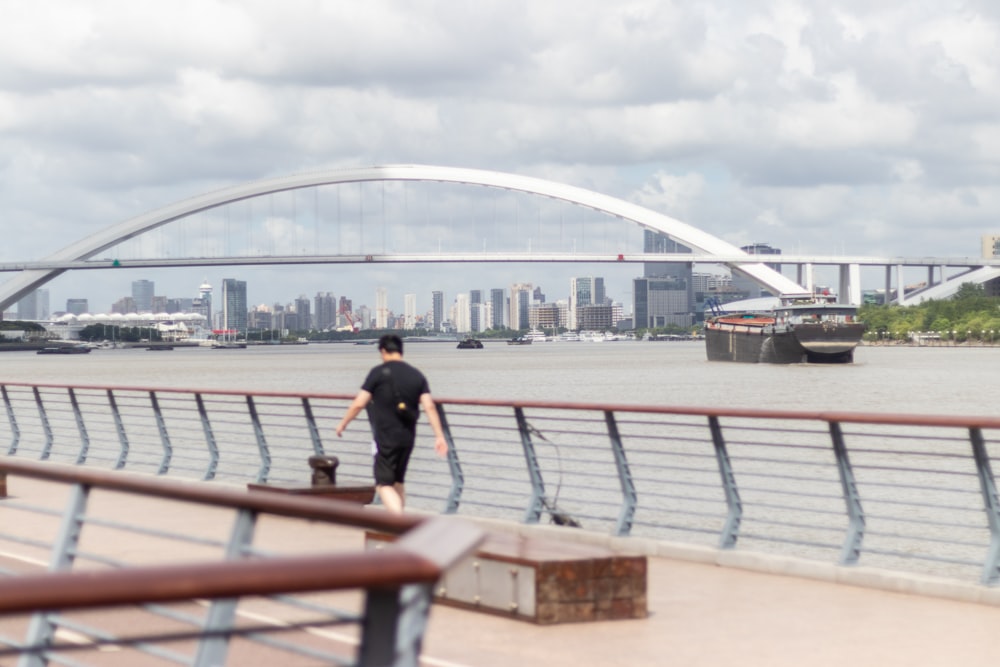 a man walking a dog across a bridge