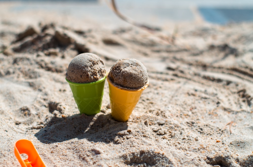 a couple of cups that are sitting in the sand