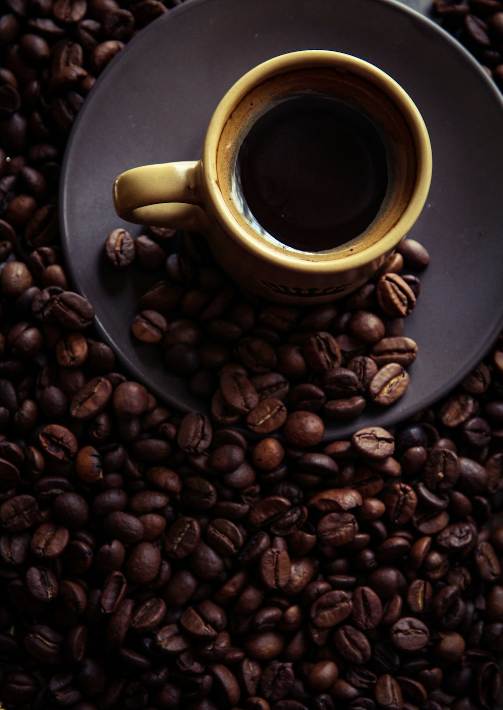 a cup of coffee sitting on top of a pile of coffee beans