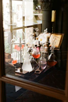 Scientific glassware with epigenetic and longevity reference chemicals under soft turquoise lighting.