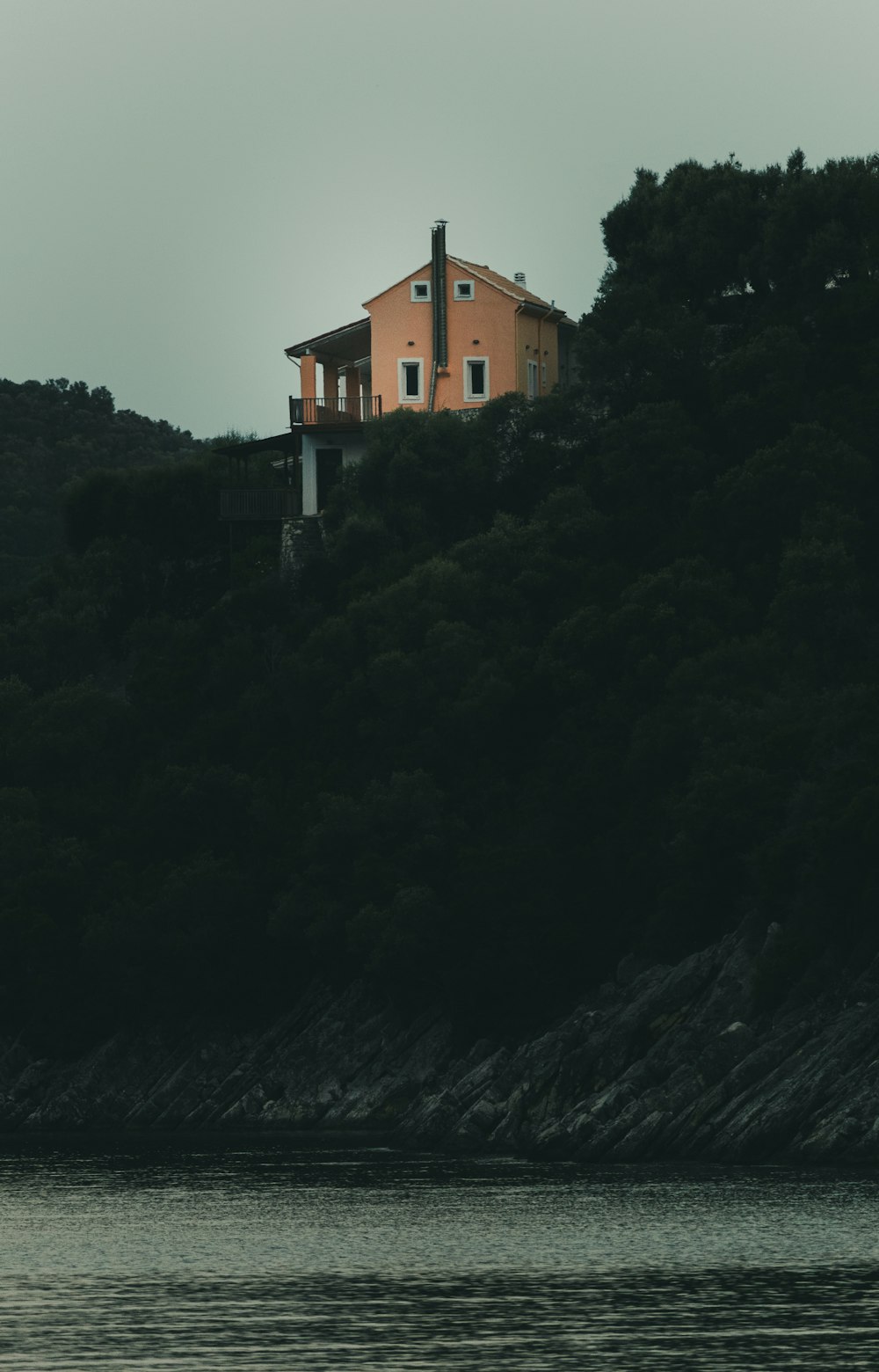 a house sitting on top of a hill next to a body of water