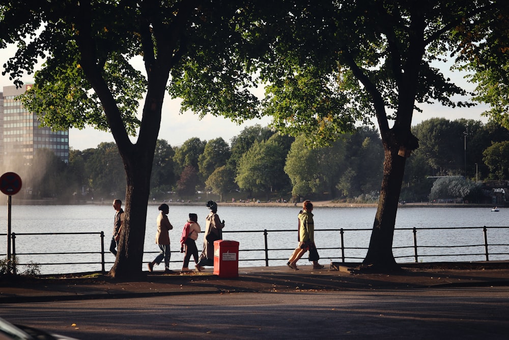 a group of people walking down a sidewalk next to a lake